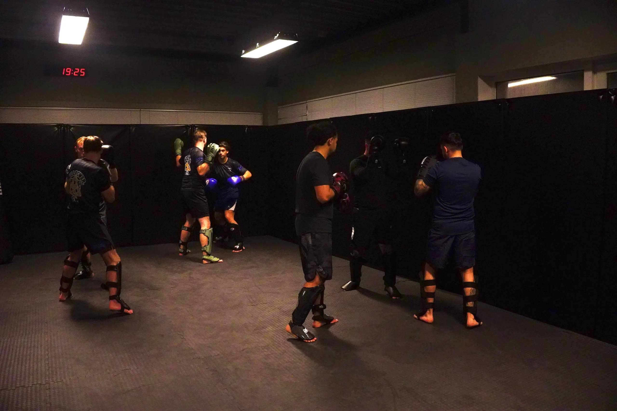Wijd beeld van de zaal tijdens een training, met de rode digitale klok aan de wand