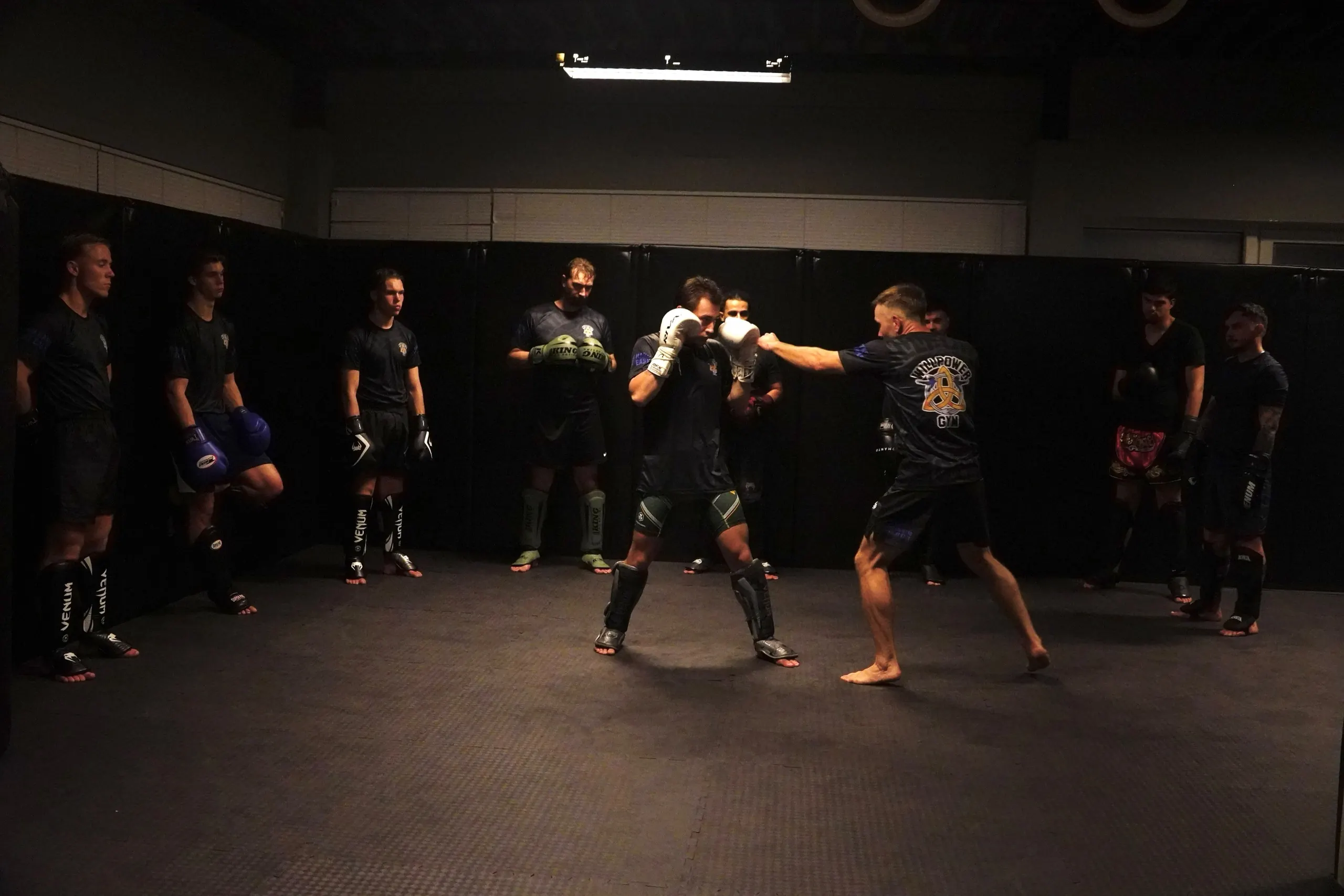 Wijd beeld van de zaal van Willpower Gym, met leden die sparren op de mat
